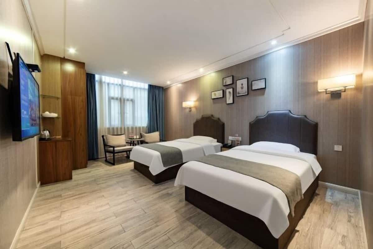 Habitación de hotel con dos camas, televisor, escritorio y una silla.