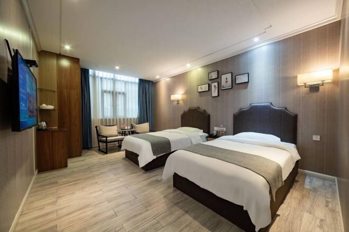 Habitación de hotel con dos camas, televisor, escritorio y silla.