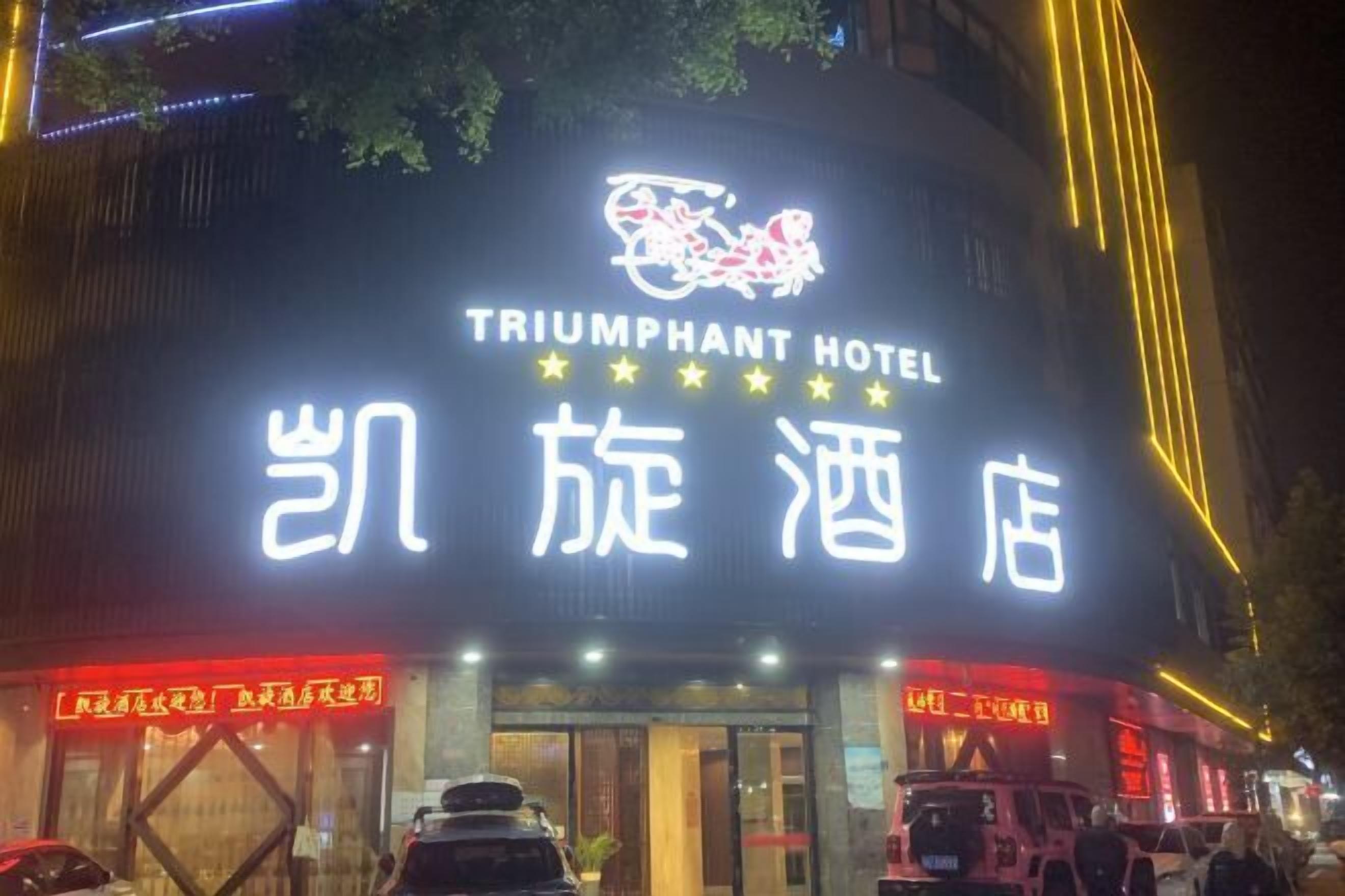 The exterior of the Triumphant Hotel with its illuminated signage and a visible entrance.