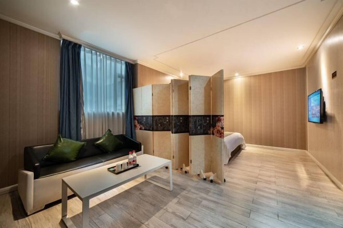 Una habitación de hotel moderna con un sofá, una mesa de centro, una cama y un televisor.