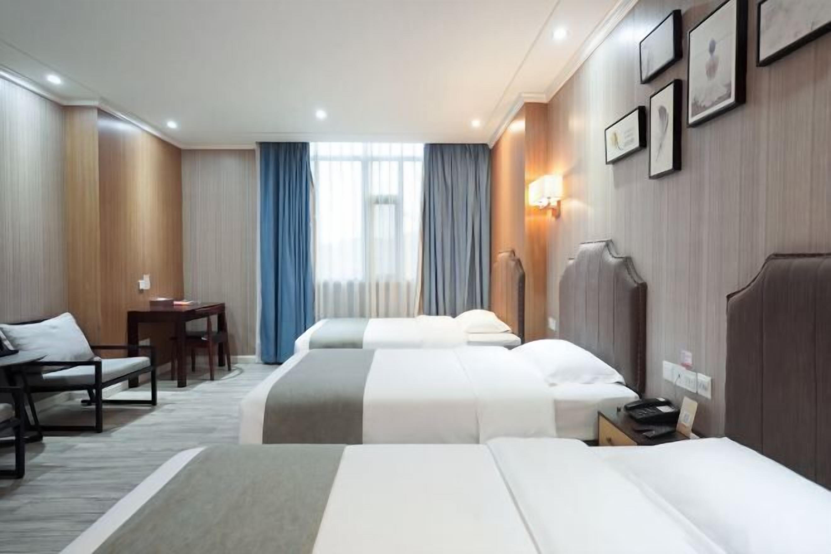 A hotel room with two beds, a desk, a chair, and a window with curtains.