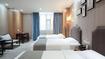 A hotel room with two beds, a desk, a chair, and a window with curtains.