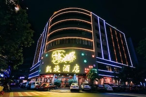 Un hotel de varios pisos con señalización iluminada y fachada curva.