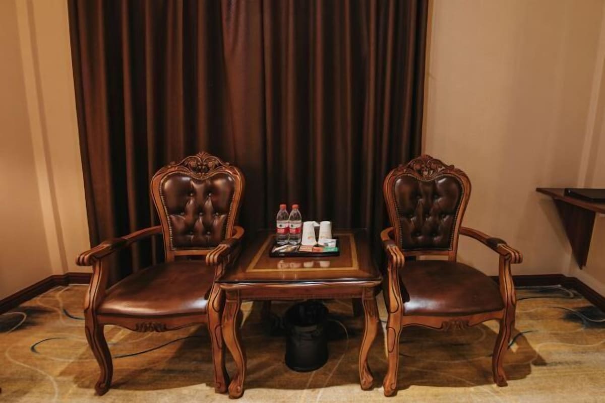 A room with two wooden chairs and a small table, with a curtain in the background.