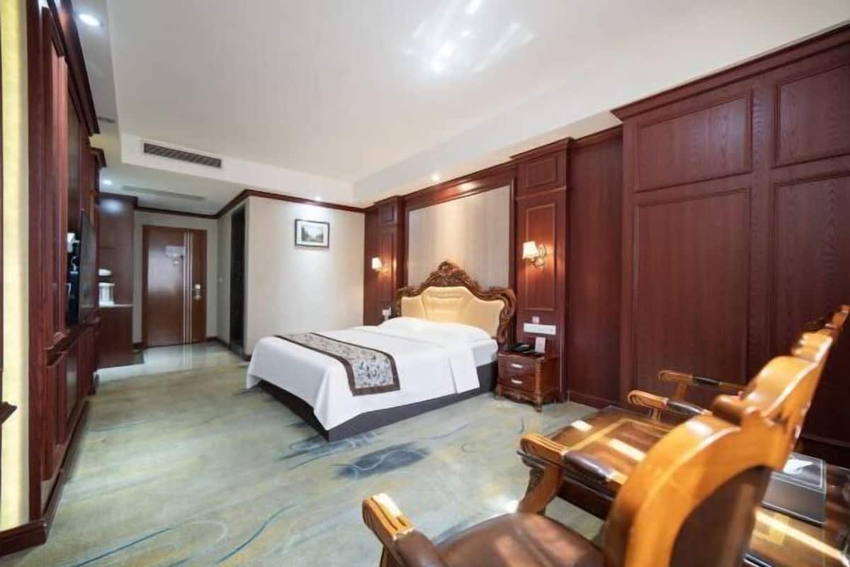 Una habitación de hotel con una cama grande, muebles de madera, un escritorio y una silla.