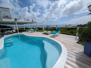 Une piscine dotée d’une terrasse, de chaises longues et offrant une vue sur l’océan.