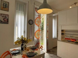 Un coin repas avec une table dressée pour quatre personnes, un vase rempli de fleurs et une fenêtre ornée de rideaux.