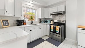 A modern kitchen with white cabinets, a built-in oven, a microwave, and a coffee maker. - Casa Soleada in Heart of East Rock 3BR | Cozy King Bed | Near DT/Yale (New Haven)