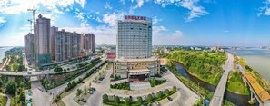 A high-rise building with a modern design, surrounded by a well-maintained urban environment, including a river and a bridge. - Guopeng International Hotel (Pingnan)