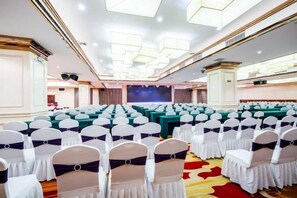 A conference room with rows of chairs, a stage, and a large screen. - Guopeng International Hotel (Pingnan)
