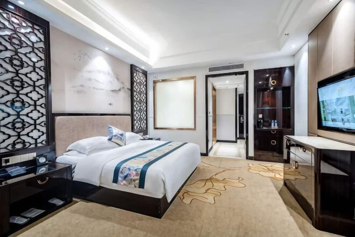 A hotel room with a bed, a TV, a desk, and a wardrobe.