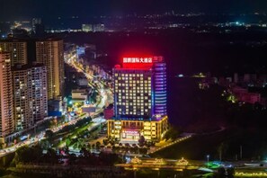 A multi-story hotel with a prominent red sign on the top, surrounded by other buildings and a busy street. - Guopeng International Hotel (Pingnan)