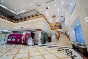 A multi-level interior with a grand staircase, a reception area, and a spacious lobby with a patterned floor.
