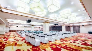 A large hall with rows of chairs and a patterned carpet, with a modern ceiling design.