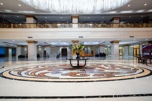 A spacious lobby with a central circular marble floor, a decorative table with flowers, and a high ceiling with a chandelier. - Guopeng International Hotel (Pingnan)