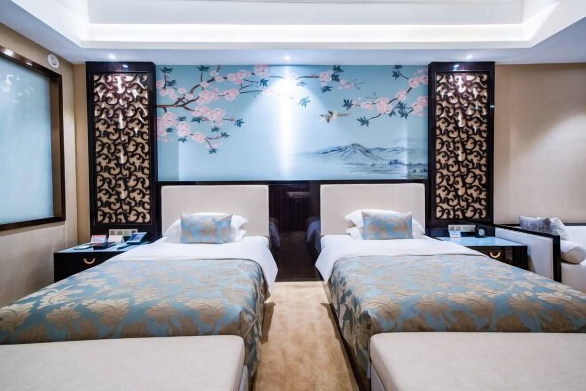 A hotel room with two beds, a large window, and a decorative wall mural.