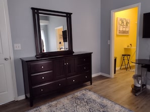 A dark wooden dresser with a mirror above it, a patterned rug, and a yellow wall in the background.