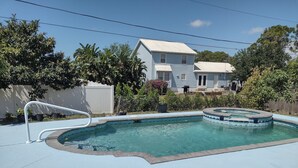 Una piscina con idromassaggio, circondata da una recinzione e alberi.