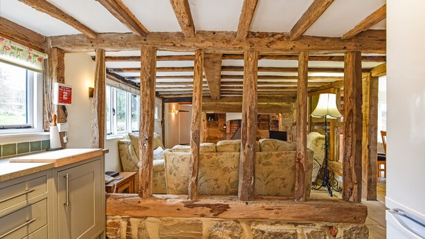 A rustic interior with exposed wooden beams, stone steps, and a cozy seating area. - Bellflower Cottage - Ashdown Forest (Haywards Heath)