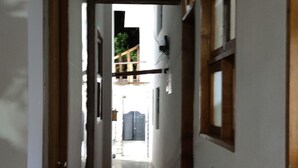 Un couloir étroit, doté d’un sol carrelé et de portes en bois de chaque côté.