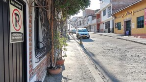 Une vue de rue avec un panneau indiquant « Stationnement interdit », un mur de briques et un immeuble à la façade jaune.