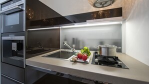 A modern kitchen with a built-in oven, a sink, a stovetop, and a chandelier. - Panorama Lake View Apt + Pool & Beach, Ghiffa, Italy (Ghiffa)