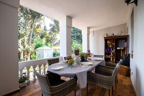 Enjoy meals in this dining area with a table for four, surrounded by wicker chairs and a view of the surrounding trees.