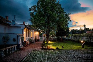 Stroll through the serene garden, surrounded by lush plants and a majestic tree, to the inviting front porch of this charming home.