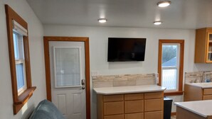 A modern kitchen with wooden cabinets, a built-in oven, and a large window.