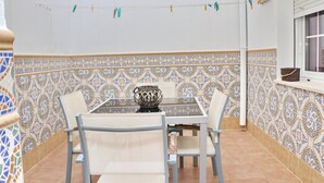 A dining area with a table and chairs, a decorative vase, and patterned tile walls.