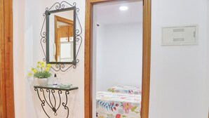 A bedroom with a bed, a bedside table with a mirror, and a small potted plant.