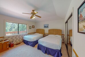 Une chambre avec deux lits, un ventilateur de plafond, une fenêtre avec des stores et un tableau encadré au mur.