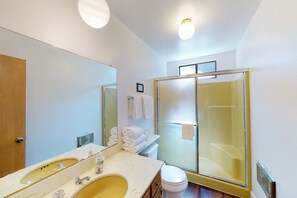 A bathroom with a large mirror, a sink, a toilet, and a glass shower enclosure.