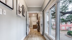 Ein Flur mit Holzdielen, einem großen Fenster und gerahmten Kunstwerken an den Wänden.
