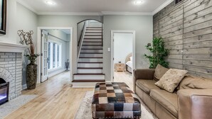 Ein geräumiges Wohnzimmer mit einer Holztreppe, einem Kamin und einem großen Fenster.
