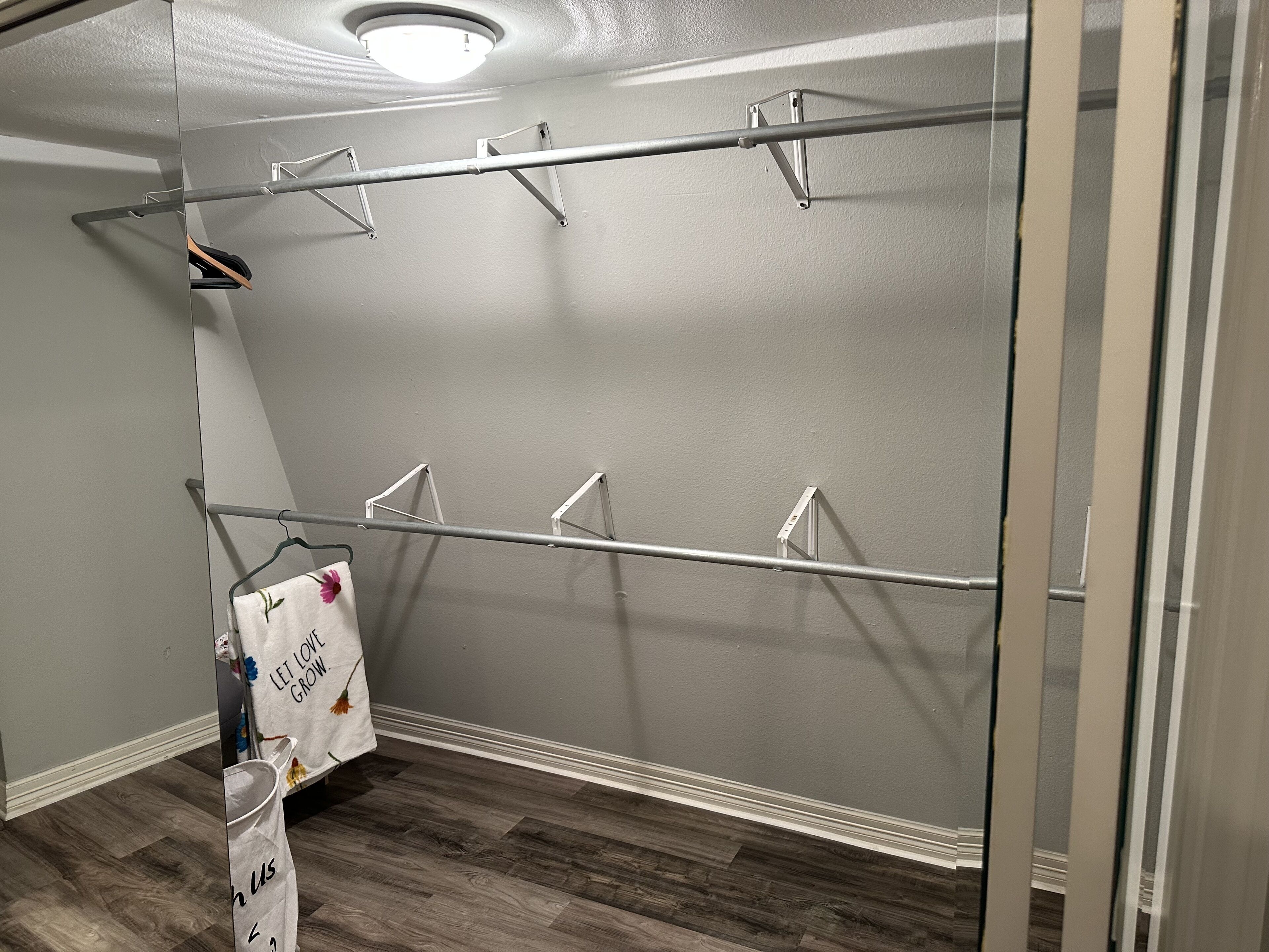 Une pièce avec un mur gris, un plancher en bois et un étendoir à linge en métal.