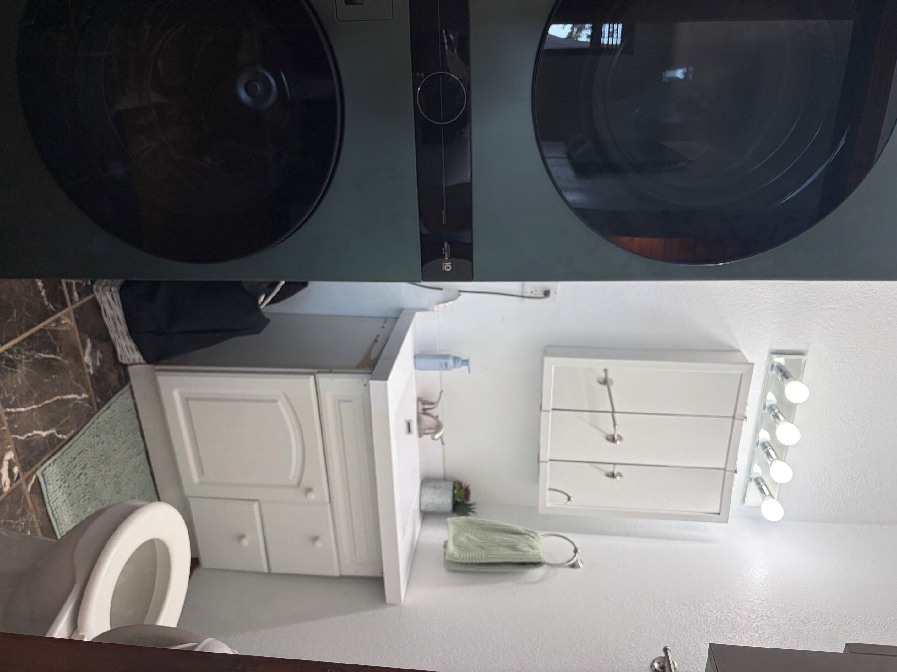 Een badkamer met toilet, wastafel, spiegel en handdoekhouder.