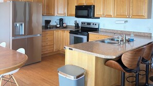 Eine moderne Küche mit Holzschränken, Edelstahlgeräten, einer Granitabdeckung und einer Bar mit Barhocker.