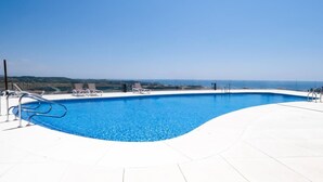 En klarblå pool med utsikt över havet och det avlägsna landskapet.