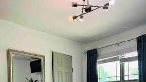 Een slaapkamer met een bed, een spiegel, een deur en een raam met gordijnen.