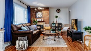 A living room with a brown leather sofa, a glass coffee table, a fireplace, a bookshelf, and a television. - Welcome to our charming and newly remodeled home, close to everything (Richfield)
