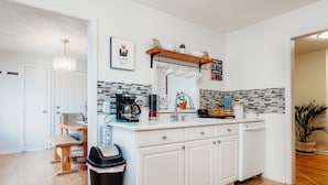 A modern kitchen with white cabinetry, a wooden dining table, and a hanging light fixture. - Welcome to our charming and newly remodeled home, close to everything (Richfield)