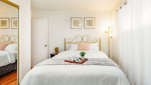A neatly arranged bedroom with a bed, a bedside table with a lamp, and two framed pictures on the wall. - Welcome to our charming and newly remodeled home, close to everything (Richfield)