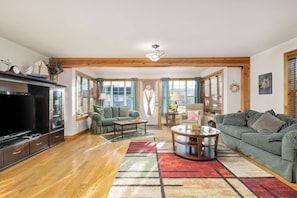 A spacious living room with a large TV, two sofas, a coffee table, and a patterned rug.