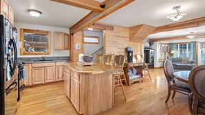 Une cuisine spacieuse dotée de meubles en bois, d’un grand îlot central et d’un coin repas avec une table et des chaises.
