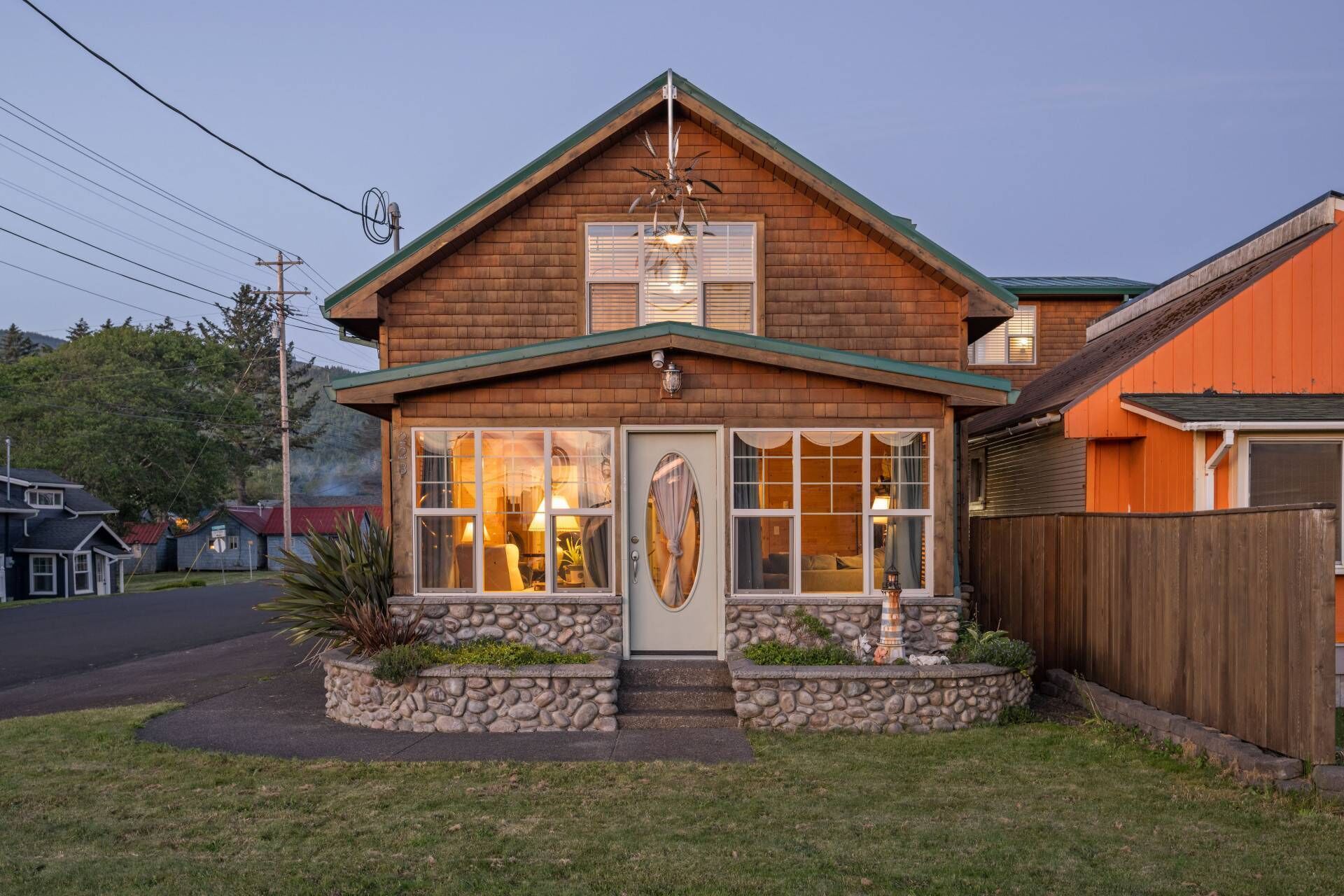 A two-story wooden house with a stone foundation, a front porch, and a garage.