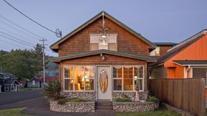 Une maison en bois à deux étages, avec des fondations en pierre, un porche à l’avant et un garage.