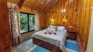 A wooden-paneled bedroom with a bed, curtains, and a nightstand.