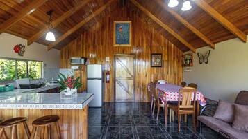 A wooden interior with a kitchen, dining area, and bar stools.