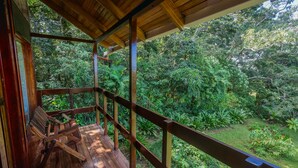 A wooden deck with a railing overlooking a lush garden.